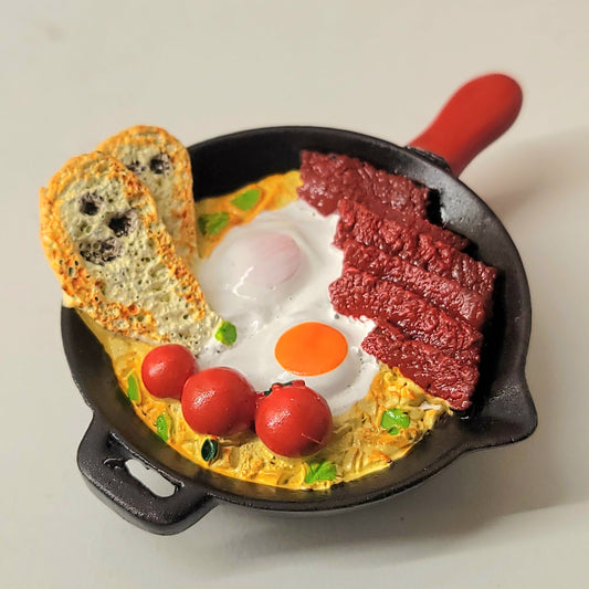 Breakfast skillet magnet close-up showing detailed eggs, bacon and pan design with red handle