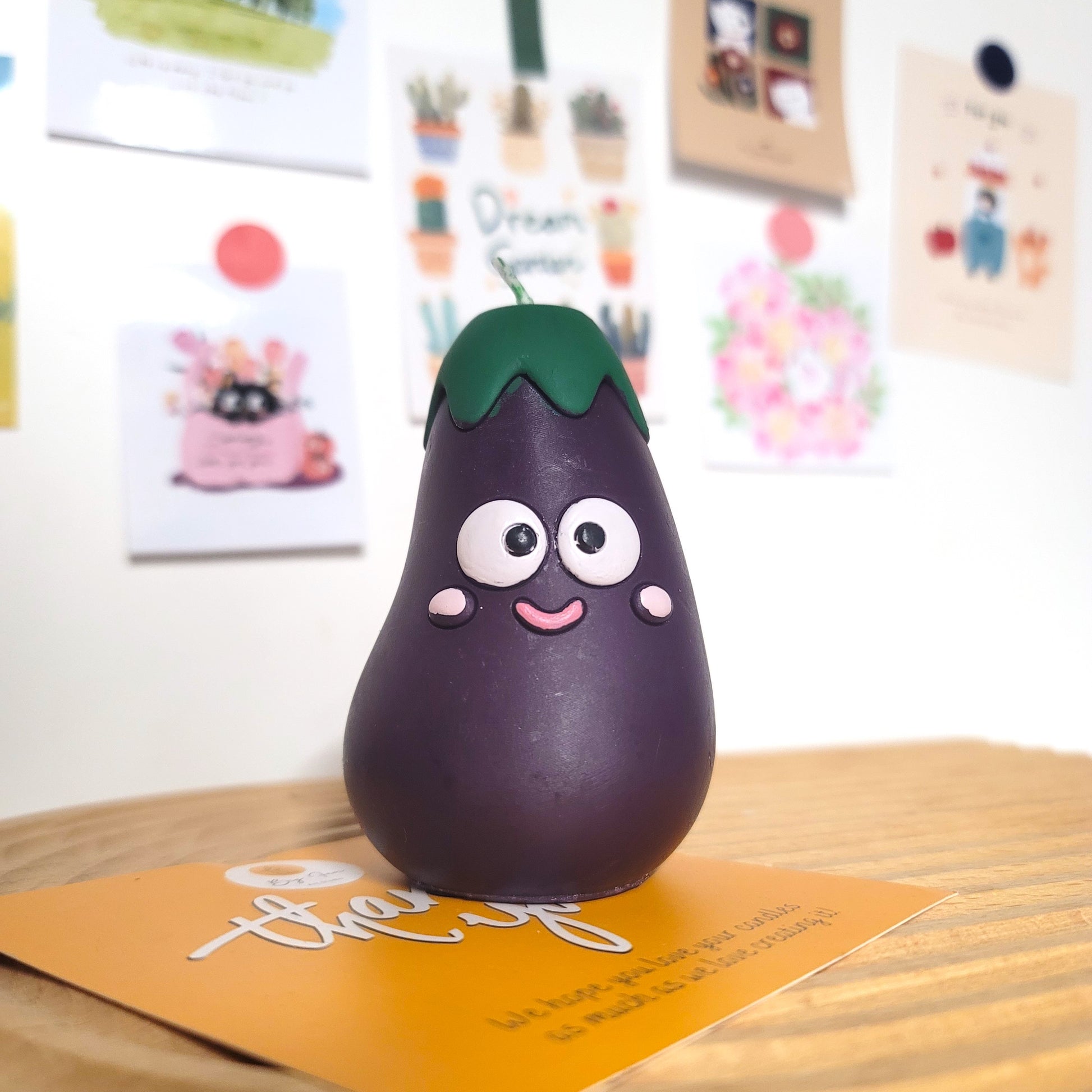 Eggplant buddy candle with adorable smiling design, cute character sculptural soy wax decor
